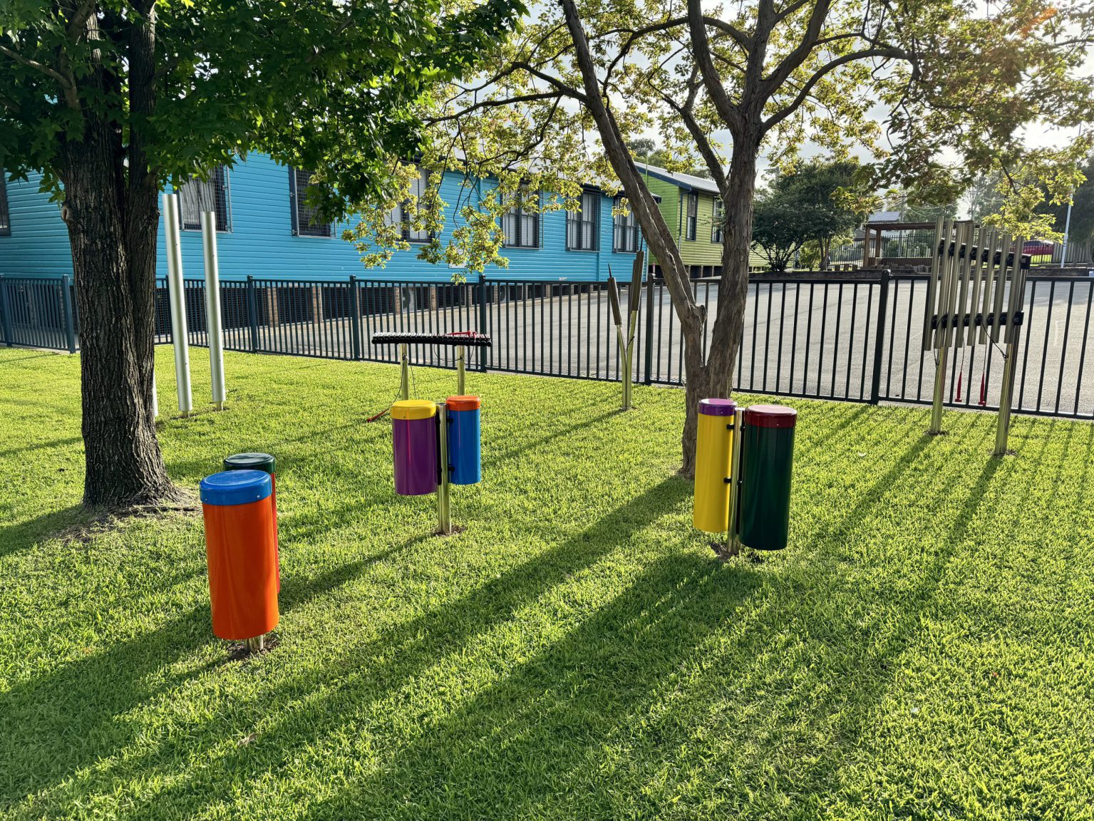 Outdoor musical instruments installed in a school playground on the grass under some trees